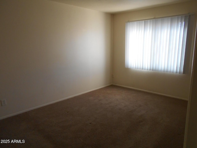 carpeted empty room featuring baseboards