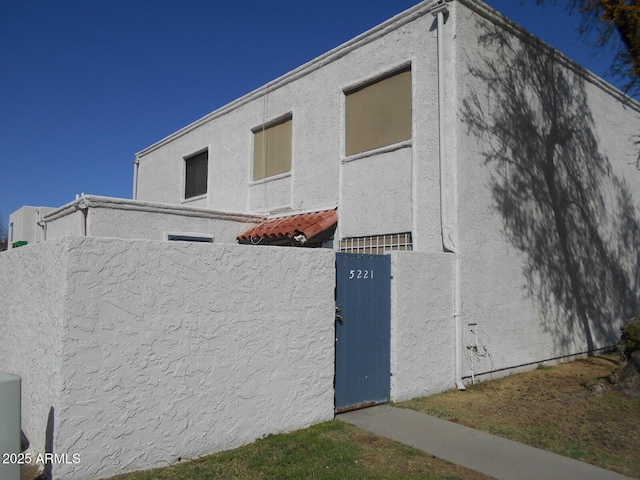 view of property exterior with stucco siding and fence