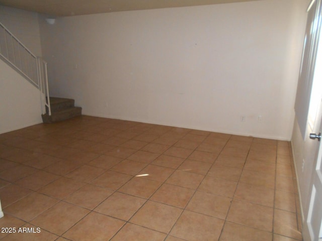 empty room featuring stairway and light tile patterned floors