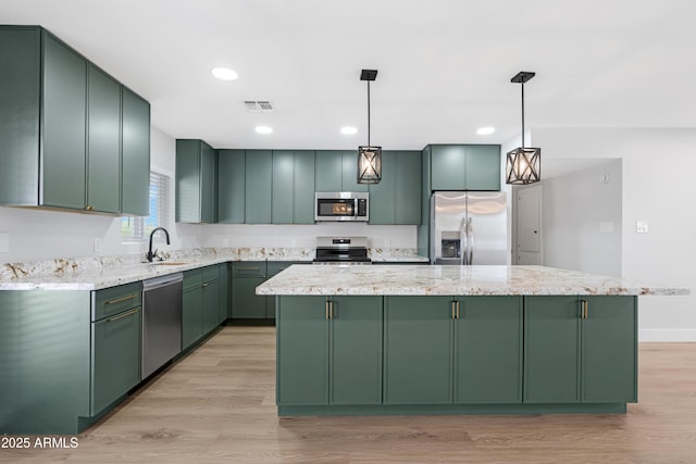 3607 N 79th Ave, Phoenix, AZ 85033 - kitchen featuring green cabinetry, stainless steel appliances, light wood-type flooring, a center island, and hanging light fixtures