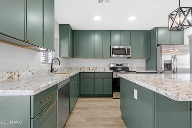 3607 N 79th Ave, Phoenix, AZ 85033 - kitchen featuring stainless steel appliances, green cabinets, a sink, light wood-type flooring, and decorative light fixtures