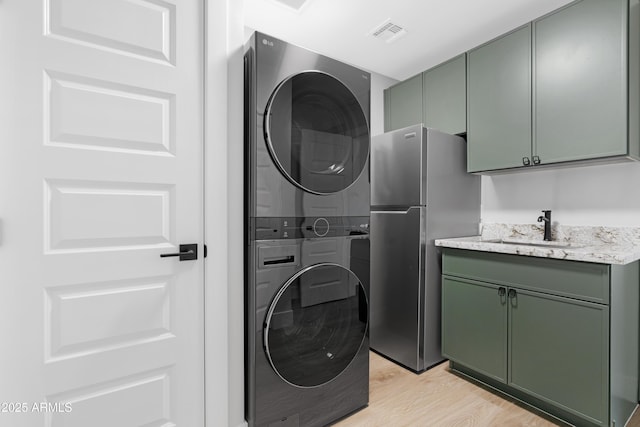3607 N 79th Ave, Phoenix, AZ 85033 - clothes washing area featuring stacked washer / dryer, cabinet space, and light wood-type flooring