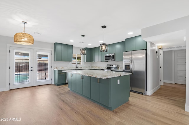 3607 N 79th Ave, Phoenix, AZ 85033 - kitchen featuring stainless steel appliances, a center island, green cabinets, light wood-type flooring, and baseboards