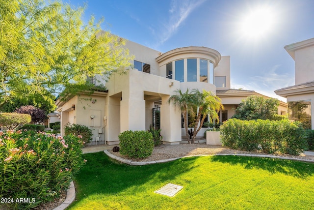 rear view of house featuring a balcony and a lawn