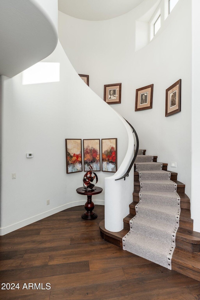 stairs with wood-type flooring and a towering ceiling