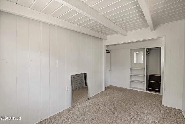 unfurnished bedroom with beamed ceiling and carpet floors