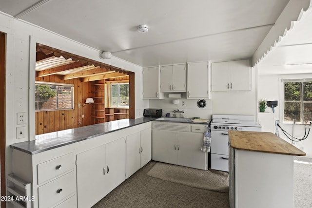 kitchen with wooden walls, a sink, butcher block countertops, white cabinetry, and white range with electric stovetop