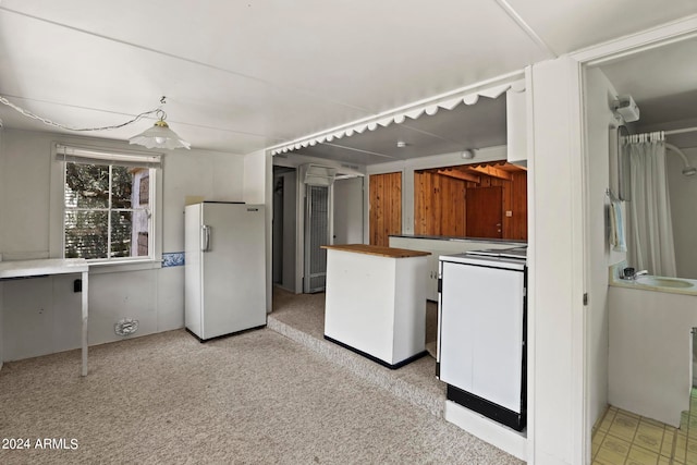 kitchen with white fridge, light carpet, and sink