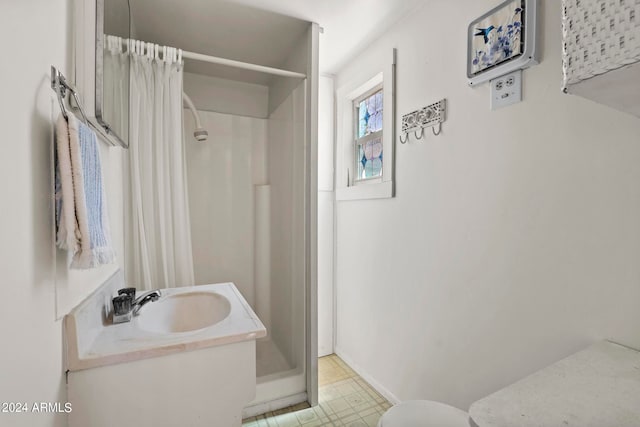 bathroom featuring tile patterned flooring, toilet, walk in shower, and vanity