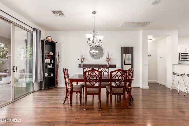 dining space with dark wood-type flooring and a chandelier