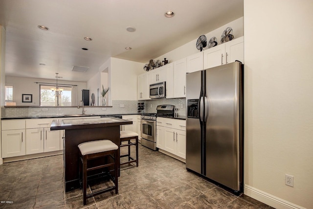 kitchen with a breakfast bar, white cabinetry, decorative light fixtures, kitchen peninsula, and stainless steel appliances