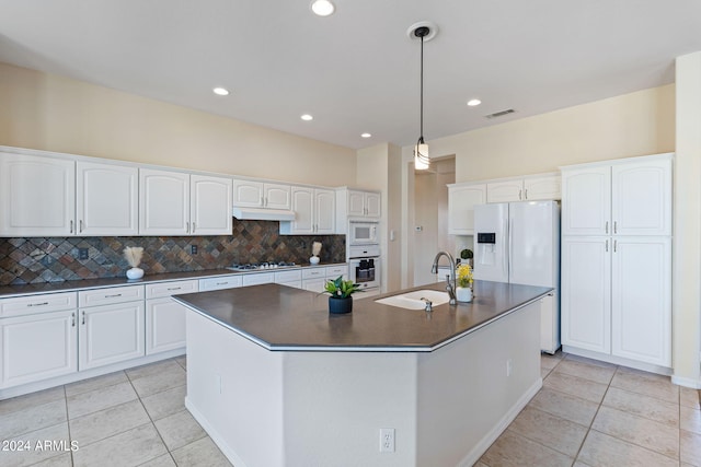 kitchen with dark countertops, visible vents, light tile patterned flooring, a sink, and white appliances