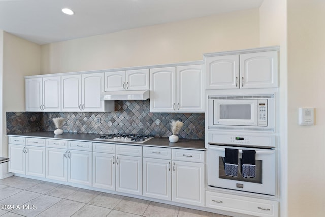 kitchen with white appliances, dark countertops, backsplash, and under cabinet range hood