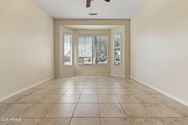 unfurnished room with light tile patterned floors, a ceiling fan, visible vents, and baseboards