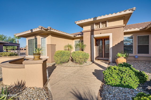 view of exterior entry featuring a tile roof and stucco siding