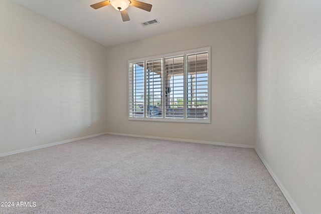 carpeted spare room featuring visible vents, ceiling fan, and baseboards