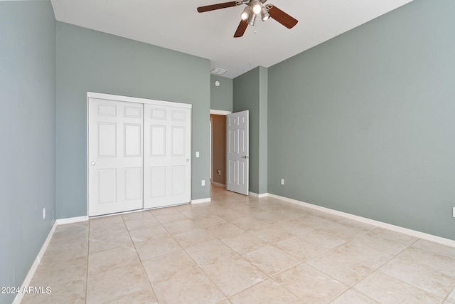 unfurnished bedroom with light tile patterned flooring, ceiling fan, and a closet