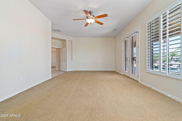 spare room featuring light carpet, visible vents, baseboards, and a ceiling fan