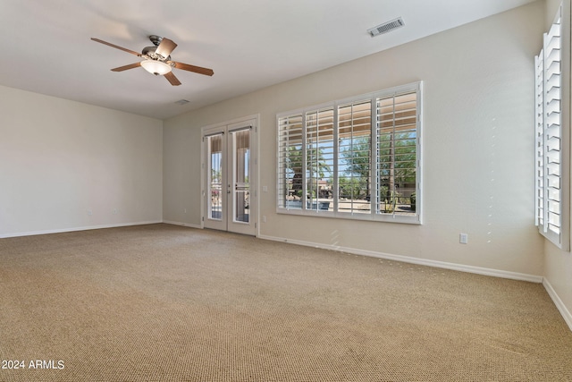 carpeted empty room featuring baseboards, a ceiling fan, visible vents, and a healthy amount of sunlight