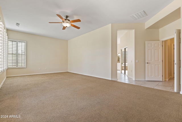 unfurnished room with a ceiling fan, light carpet, visible vents, and light tile patterned flooring