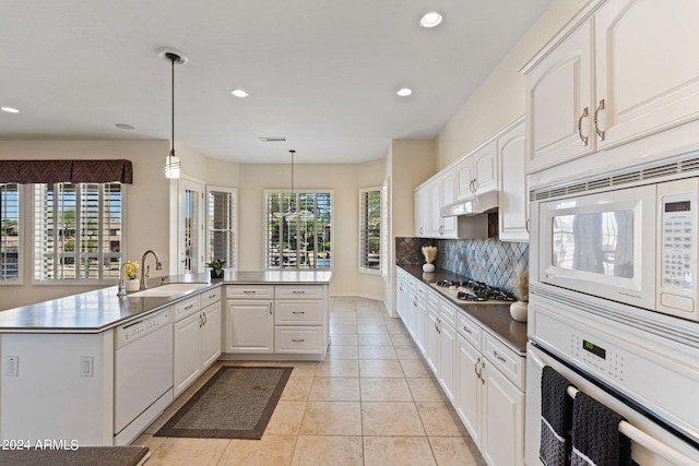 kitchen featuring white appliances, backsplash, white cabinets, and a sink