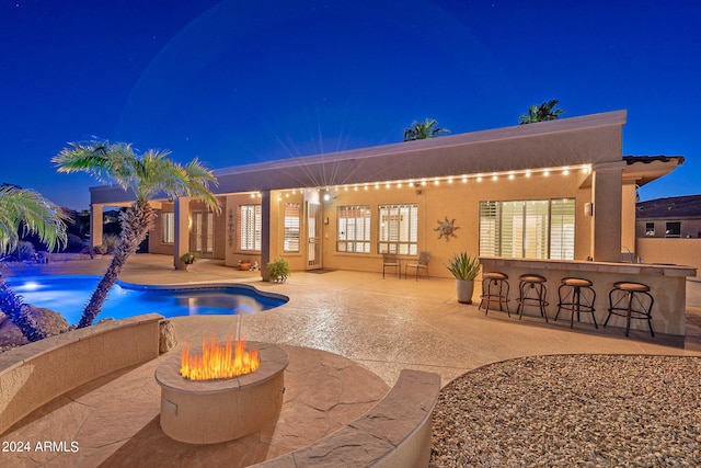 pool at twilight featuring a bar and a patio area