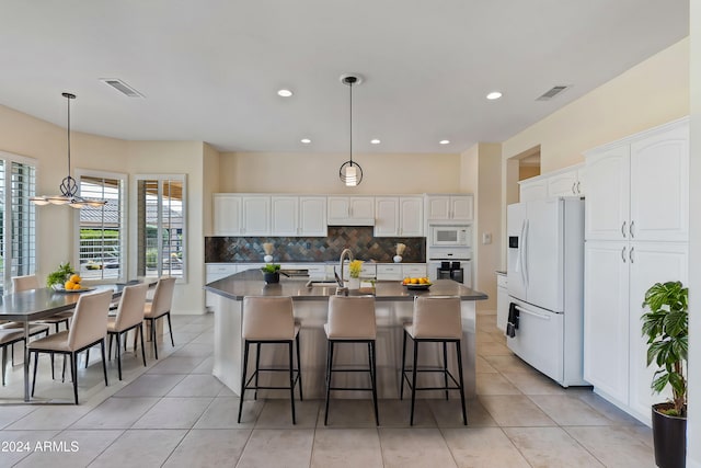 kitchen featuring white appliances, tasteful backsplash, visible vents, dark countertops, and white cabinetry