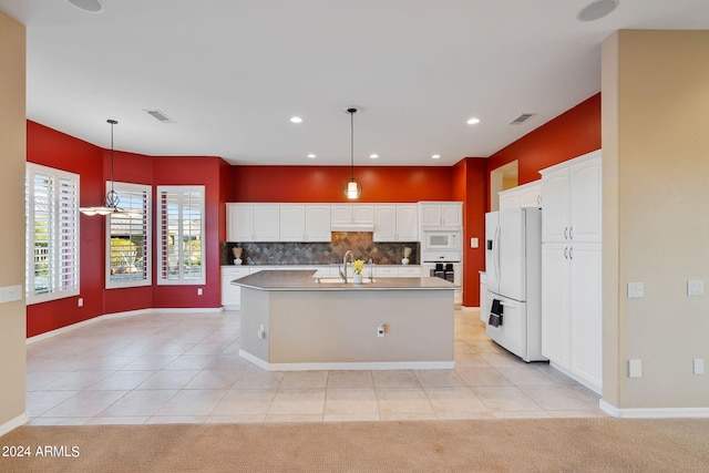 kitchen featuring an island with sink, light carpet, white appliances, and white cabinetry