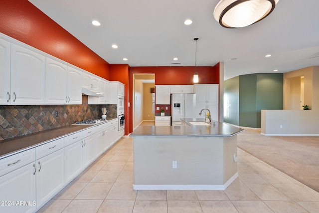 kitchen featuring white appliances, pendant lighting, light carpet, a kitchen island with sink, and white cabinets