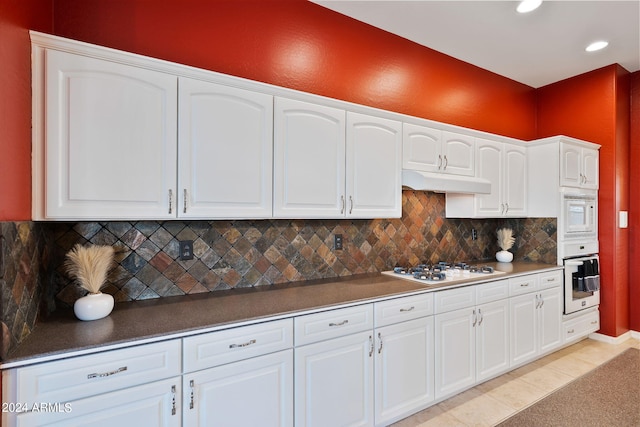 kitchen featuring white appliances, light tile patterned flooring, white cabinets, and decorative backsplash