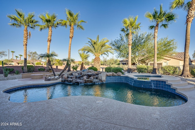 view of swimming pool with a pool with connected hot tub, a patio area, and fence