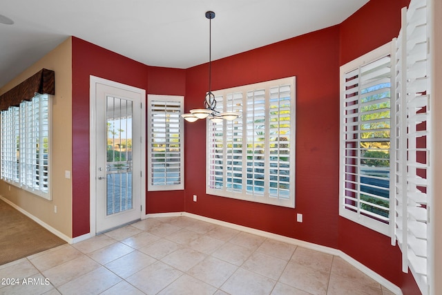 unfurnished dining area with a notable chandelier and light tile patterned floors