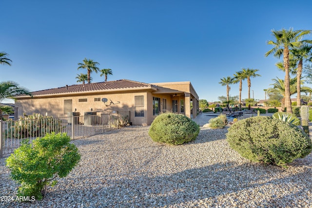 rear view of property with a tiled roof, a patio area, fence, and stucco siding