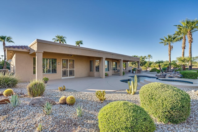 rear view of property with an outdoor pool, a patio area, a ceiling fan, and stucco siding