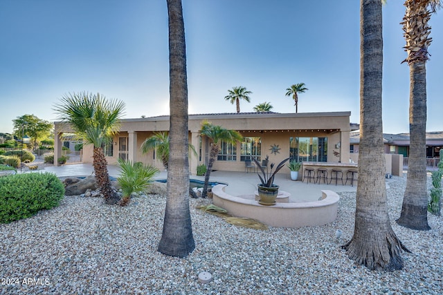 back of property featuring outdoor dry bar, a patio area, and stucco siding