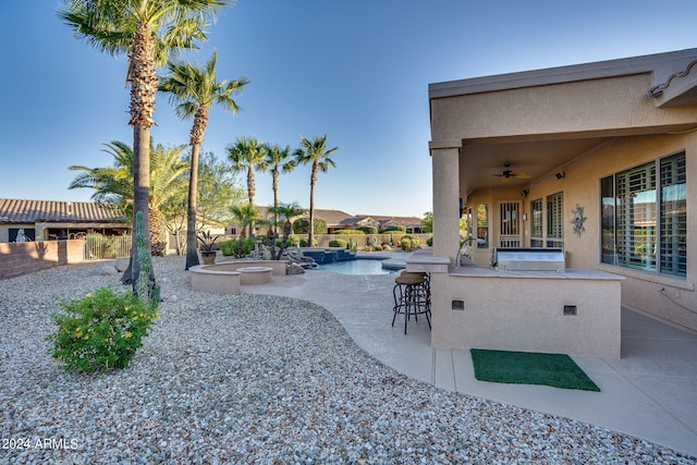 view of patio / terrace with an outdoor kitchen, fence, outdoor wet bar, and a ceiling fan