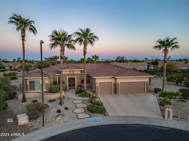 mediterranean / spanish house with an attached garage, fence, a tile roof, concrete driveway, and stucco siding