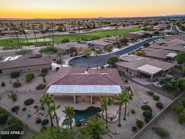 aerial view at dusk featuring a residential view and view of golf course