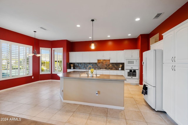 kitchen featuring white cabinets, decorative light fixtures, white appliances, an island with sink, and tasteful backsplash