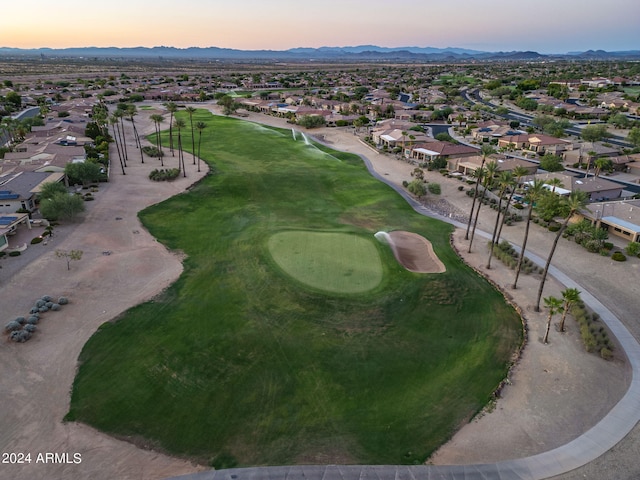 aerial view at dusk featuring a residential view, view of golf course, and a mountain view