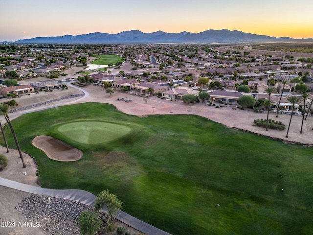 aerial view at dusk featuring view of golf course, a residential view, and a mountain view