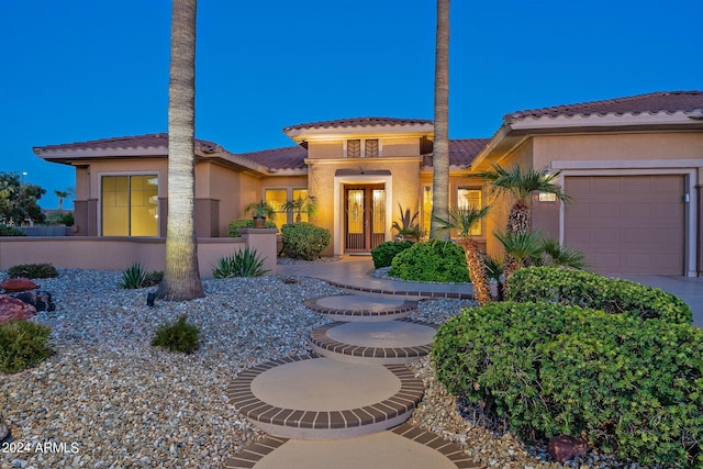 mediterranean / spanish-style home featuring a garage, a tile roof, and stucco siding