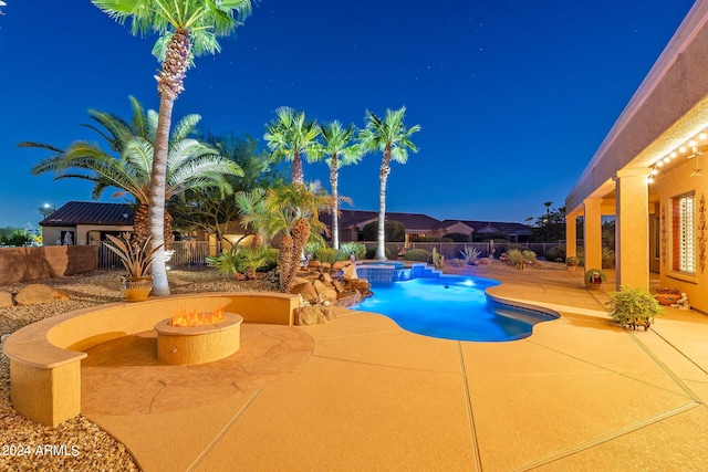 view of swimming pool featuring an outdoor fire pit, a pool with connected hot tub, a patio area, and a fenced backyard