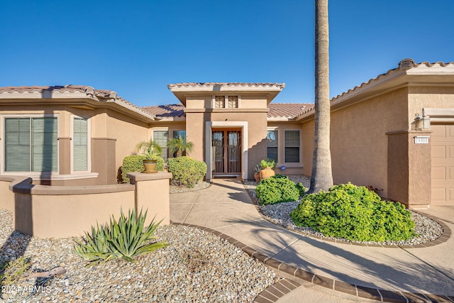 property entrance featuring an attached garage, a tile roof, and stucco siding