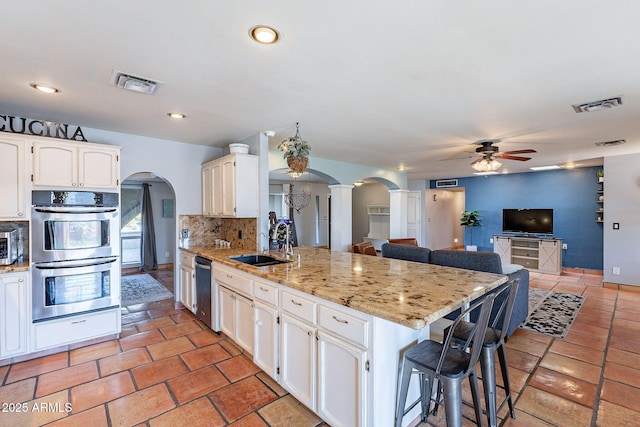 kitchen featuring sink, white cabinets, backsplash, light stone counters, and stainless steel appliances