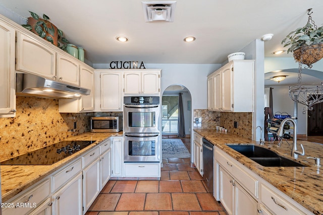 kitchen featuring sink, white cabinets, decorative backsplash, stainless steel appliances, and light stone countertops