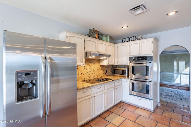 kitchen with tasteful backsplash, light stone countertops, appliances with stainless steel finishes, and white cabinetry