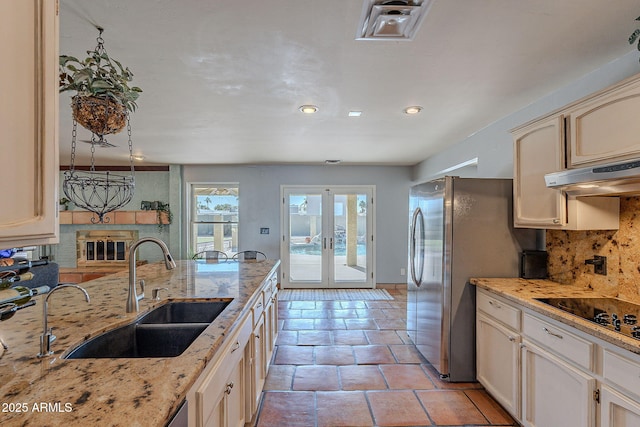 kitchen with sink, tasteful backsplash, black electric stovetop, a fireplace, and french doors