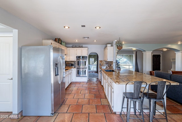 kitchen featuring sink, a kitchen breakfast bar, light stone counters, kitchen peninsula, and stainless steel appliances