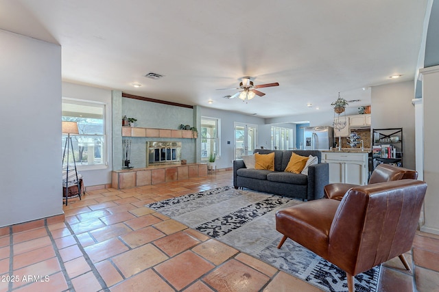 living room featuring light tile patterned floors, a fireplace, and ceiling fan